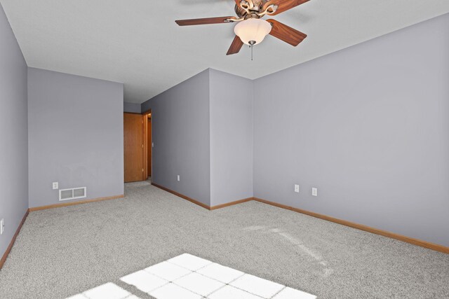 carpeted spare room with visible vents, ceiling fan, and baseboards