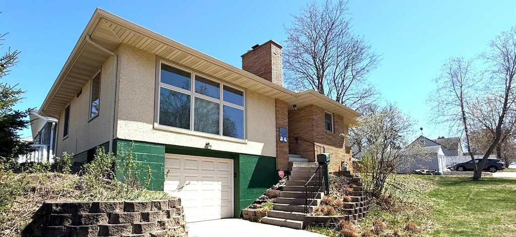 view of front of house featuring stairway, an attached garage, a chimney, and stucco siding
