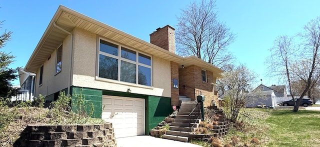 view of front of house featuring stairway, an attached garage, a chimney, and stucco siding