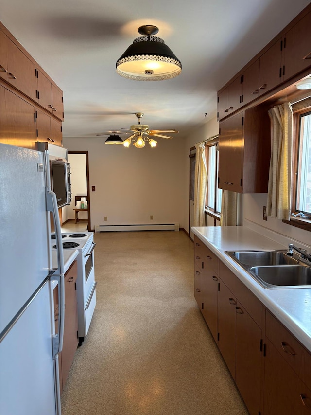 kitchen featuring a sink, light floors, light countertops, white appliances, and a baseboard radiator