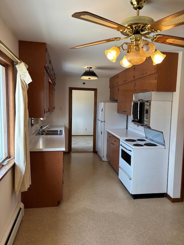 kitchen with light floors, light countertops, baseboard heating, white appliances, and a sink