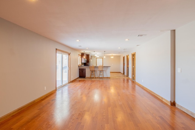 unfurnished living room featuring visible vents, recessed lighting, baseboards, and light wood-type flooring