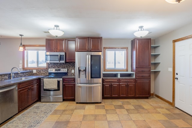 kitchen featuring baseboards, a sink, decorative backsplash, stainless steel appliances, and dark countertops