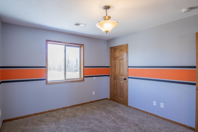 carpeted spare room with visible vents and baseboards