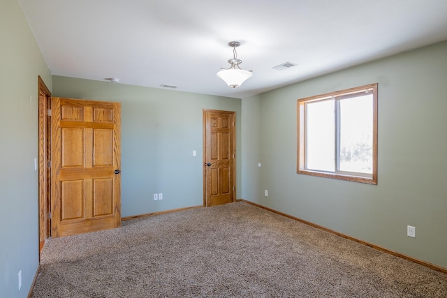 carpeted empty room featuring visible vents and baseboards