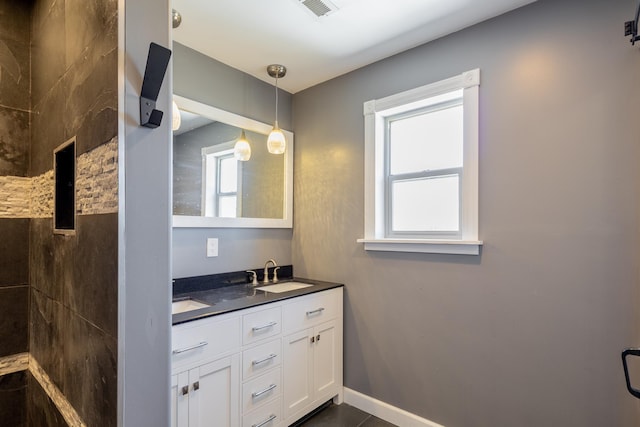 bathroom featuring double vanity, plenty of natural light, baseboards, and a sink