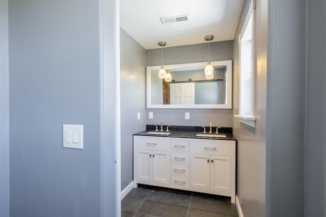 full bath featuring double vanity, visible vents, baseboards, and a sink