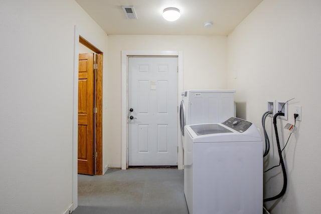 clothes washing area with visible vents, washer and dryer, and laundry area