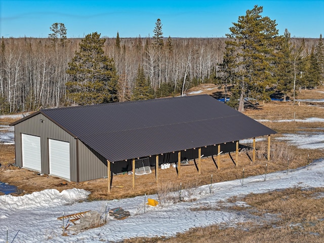 exterior space with an outdoor structure, an outbuilding, a forest view, and a detached garage