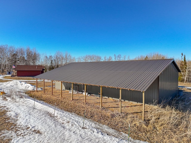 snow covered property featuring an outbuilding and metal roof