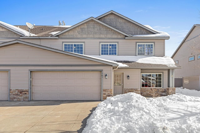 view of front of property featuring a garage, stone siding, and driveway