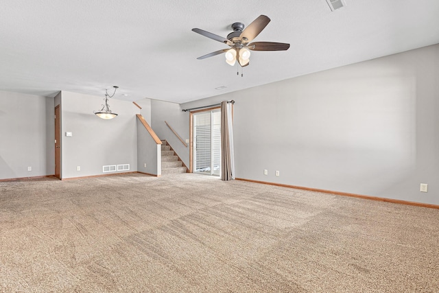 spare room featuring carpet, baseboards, visible vents, a ceiling fan, and stairs