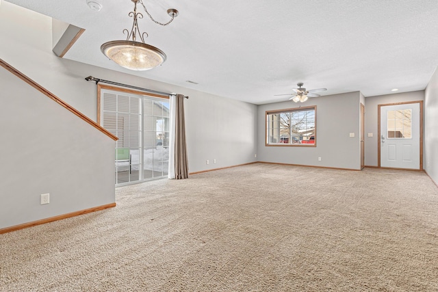 unfurnished living room featuring baseboards, carpet, ceiling fan, and a textured ceiling