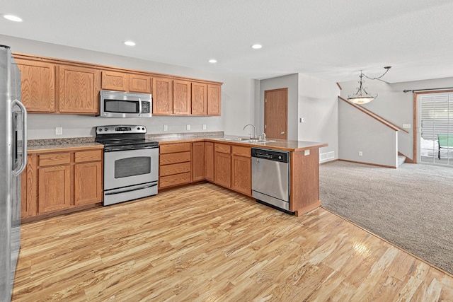 kitchen with visible vents, open floor plan, a peninsula, stainless steel appliances, and a sink