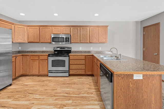 kitchen with light wood-type flooring, a sink, recessed lighting, stainless steel appliances, and a peninsula