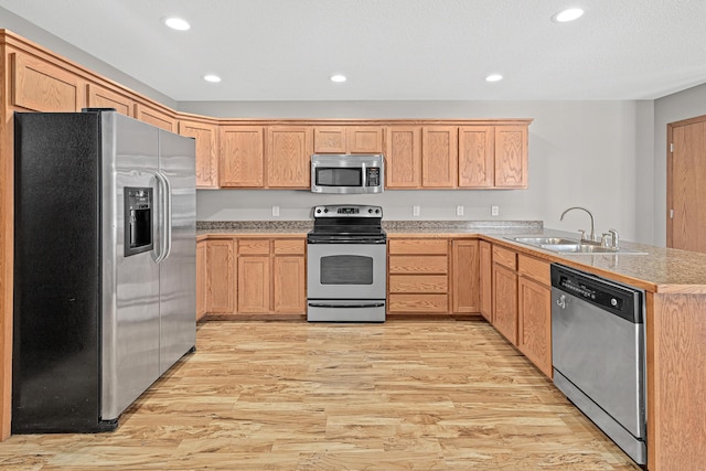 kitchen featuring recessed lighting, light wood-style flooring, appliances with stainless steel finishes, a peninsula, and a sink