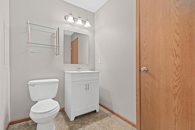 bathroom featuring toilet, vanity, and baseboards