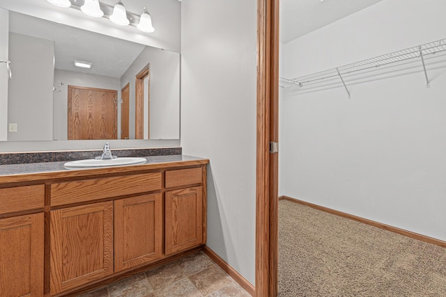 bathroom featuring vanity, a walk in closet, and baseboards