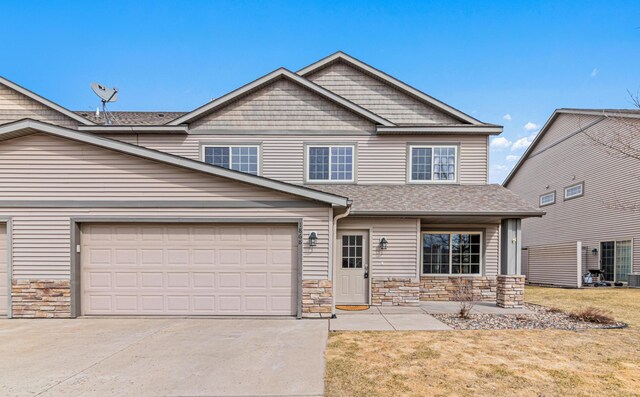 view of front of home featuring stone siding, an attached garage, a front lawn, and concrete driveway