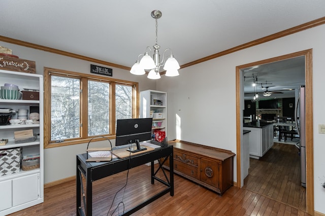 office area with ceiling fan with notable chandelier, hardwood / wood-style floors, a fireplace, and ornamental molding