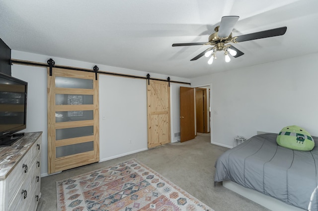 bedroom featuring light colored carpet, baseboards, a barn door, and a ceiling fan