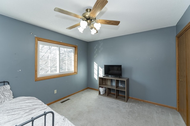 bedroom with a ceiling fan, visible vents, baseboards, a closet, and light colored carpet