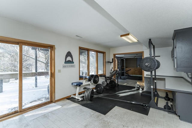 workout room featuring a wealth of natural light, visible vents, light floors, and baseboards