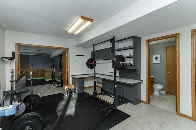 exercise area featuring tile patterned floors, baseboards, and a textured ceiling