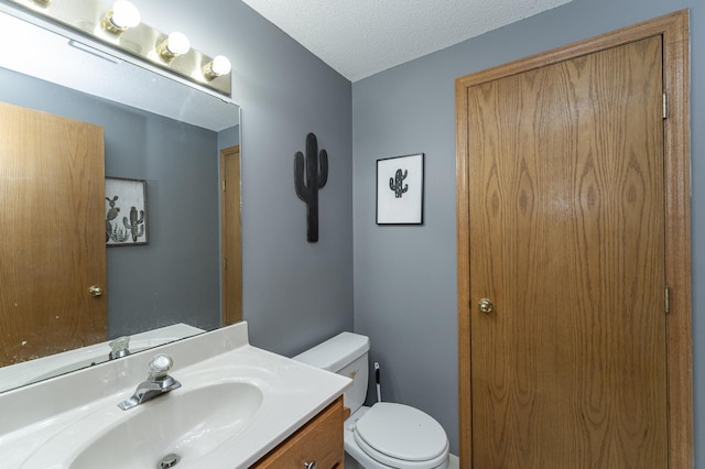 bathroom with vanity, toilet, and a textured ceiling