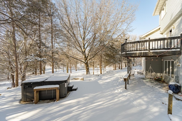 snowy yard with a wooden deck and a hot tub