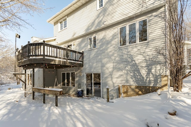 snow covered back of property featuring a wooden deck