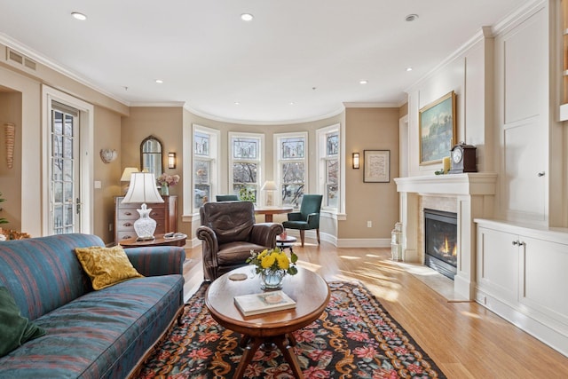 living area featuring a fireplace with flush hearth, light wood-type flooring, visible vents, and ornamental molding