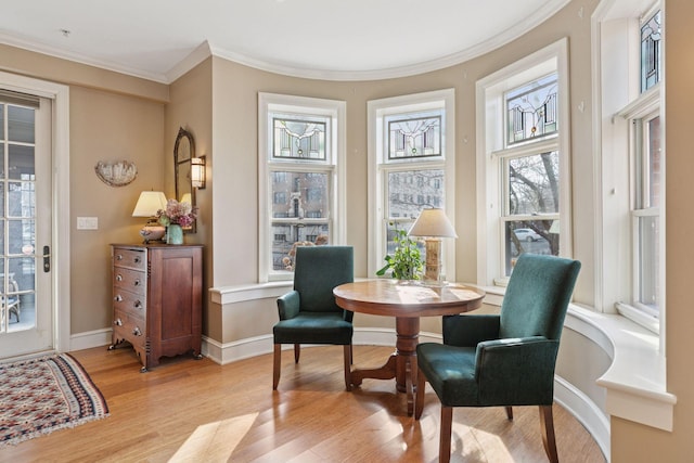 living area featuring light wood-style flooring, baseboards, and ornamental molding