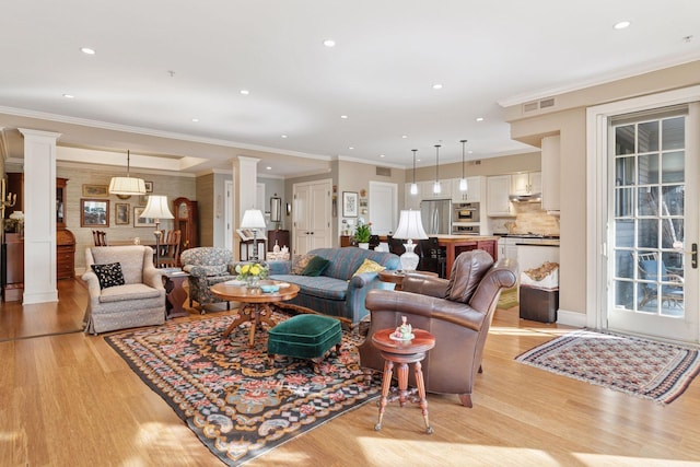 living area with light wood-style flooring, decorative columns, recessed lighting, and visible vents