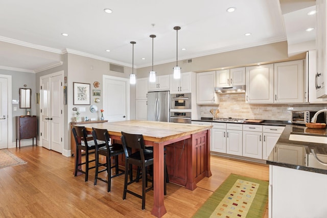 kitchen with visible vents, a sink, stainless steel appliances, under cabinet range hood, and wood counters