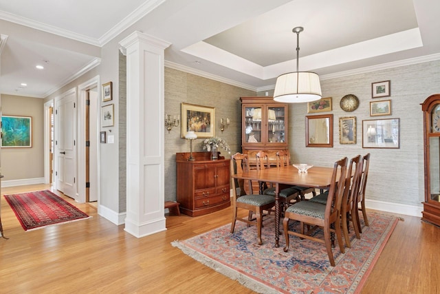 dining room with a tray ceiling, decorative columns, and baseboards