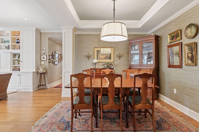 dining room featuring a tray ceiling, light wood-type flooring, and baseboards