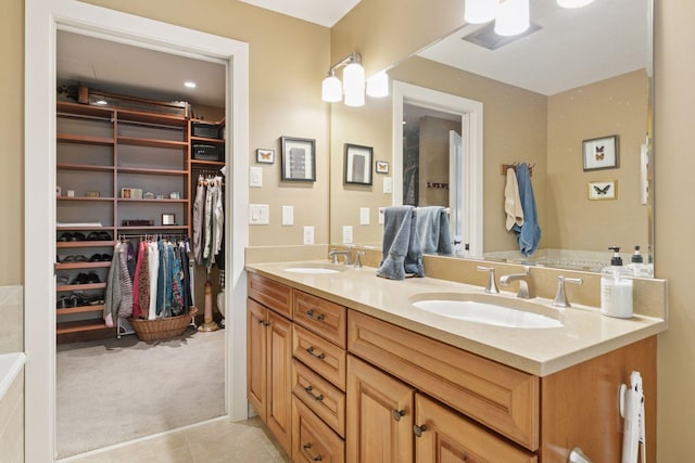 bathroom with a walk in closet, double vanity, tile patterned flooring, and a sink