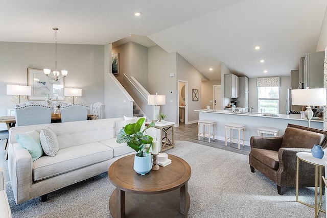 living area with lofted ceiling, recessed lighting, stairway, an inviting chandelier, and wood finished floors