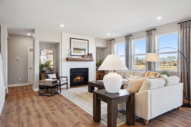 living room with recessed lighting, a fireplace, wood finished floors, and baseboards