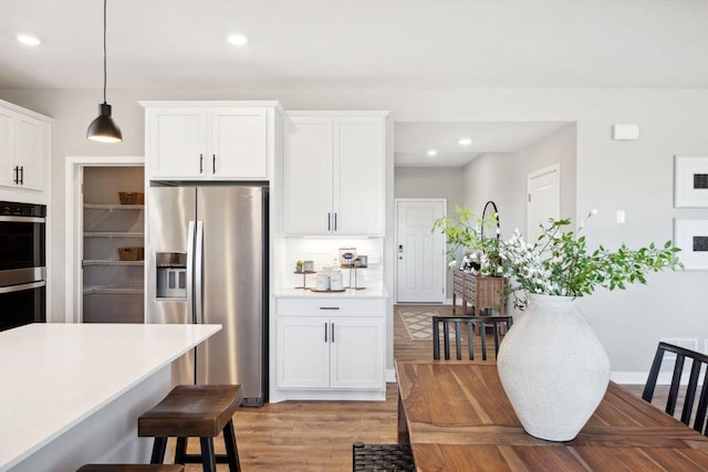 kitchen with a breakfast bar area, stainless steel appliances, tasteful backsplash, light countertops, and white cabinetry