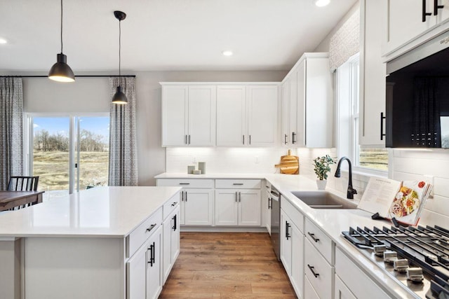 kitchen featuring appliances with stainless steel finishes, light countertops, light wood-type flooring, pendant lighting, and a sink