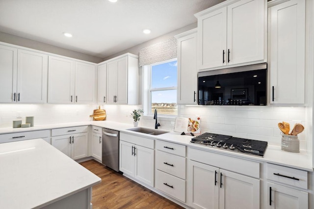 kitchen featuring appliances with stainless steel finishes, light countertops, light wood-type flooring, white cabinetry, and a sink