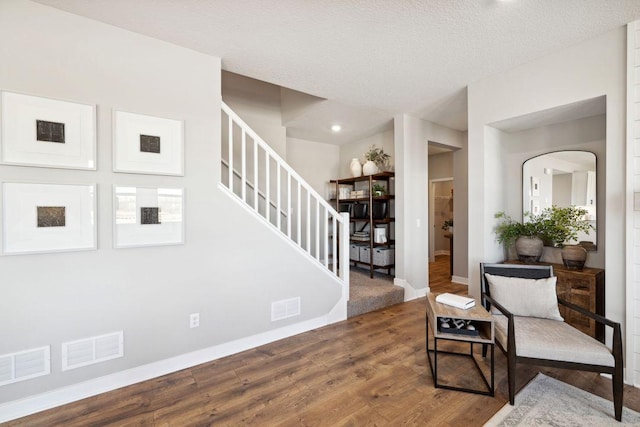 living area featuring stairs, visible vents, baseboards, and wood finished floors