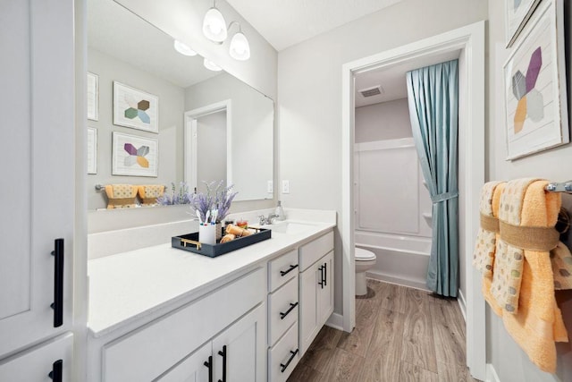 bathroom featuring visible vents, toilet, wood finished floors, tub / shower combination, and vanity