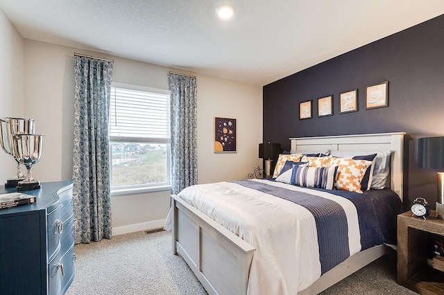 bedroom with baseboards, visible vents, and light colored carpet