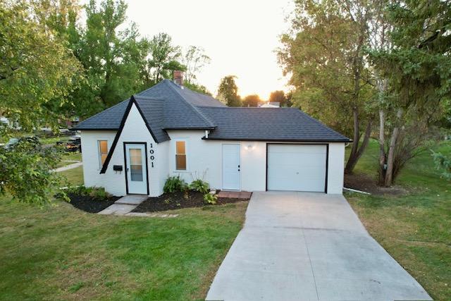 view of front facade with a front lawn, a garage, driveway, and roof with shingles