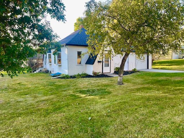 view of side of property featuring a yard, a garage, and driveway