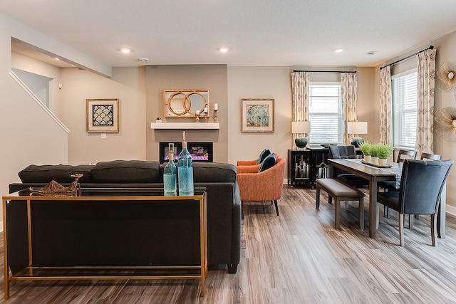 living area featuring recessed lighting, wood finished floors, and a glass covered fireplace