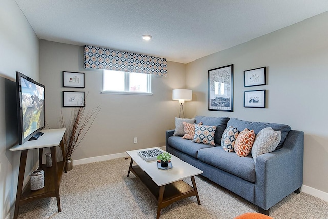 living area with light colored carpet, a textured ceiling, and baseboards